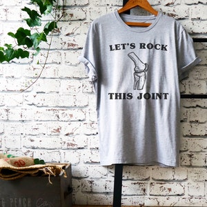 May include: A gray t-shirt with a black graphic of a knee bone and the text "Let's Rock This Joint".