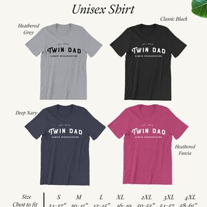 May include: Unisex t-shirt with the text "Twin Dad" in a vintage style font. The shirt is available in five colors: heather grey, classic black, deep navy, heather fuscia, and white. The size chart shows chest measurements in inches.