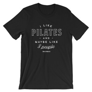 Pode incluir: Camiseta preta com texto branco que diz "Eu gosto de Pilates - e - talvez como 3 pessoas" com o texto "Stag & Peach Co" abaixo.