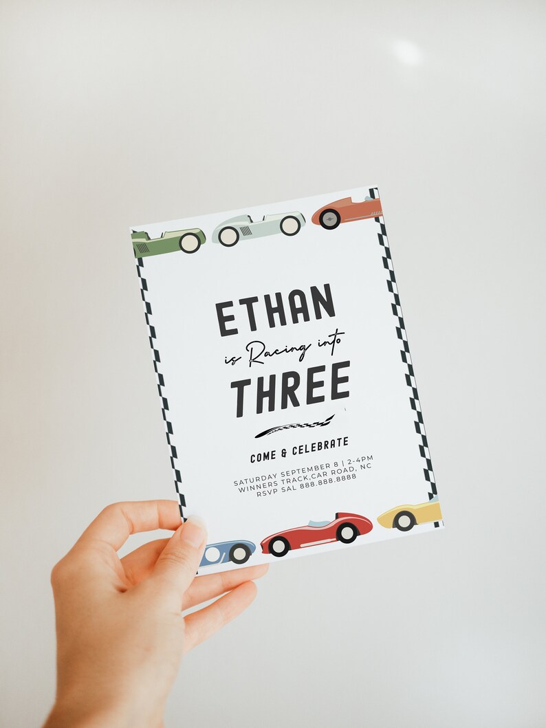 May include: A white invitation card with black text that reads "Ethan is Racing into Three" and "Come & Celebrate". The card is decorated with colourful cartoon race cars and a black and white chequered pattern.