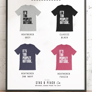 Puede incluir: Un dise&ntilde;o de camiseta gr&aacute;fica con el texto "It's Too Peopley Outside." La camiseta est&aacute; disponible en cinco colores: gris jaspeado, negro cl&aacute;sico, azul tinta jaspeado, fucsia jaspeado y blanco.