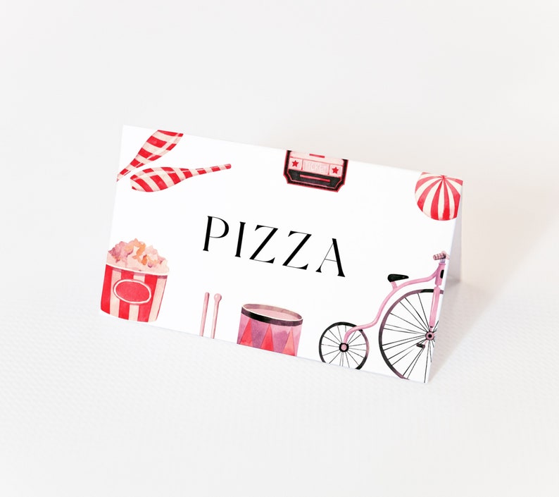May include: A white card with red and white circus-themed illustrations, including a popcorn bucket, a drum, a unicycle, and a striped tent. The text "PIZZA" is printed in black on the card.