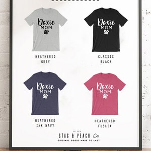May include: Four different color options for a t-shirt with the text "Doxie Mom" and a paw print. The colors are heather grey, classic black, heather ink navy, and heather fuscia.