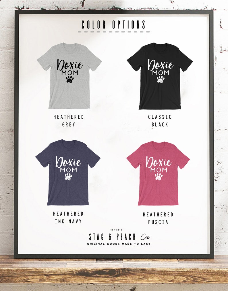 May include: Four different color options for a t-shirt with the text "Doxie Mom" and a paw print. The colors are heather grey, classic black, heather ink navy, and heather fuscia.