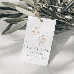 Könnte beinhalten: Weißes Dankeschön-Etikett mit goldenen Akzenten. Das Etikett zeigt ein Sonnen- und Monddesign mit Sternen. Der Text lautet "Vielen Dank für Ihr Kommen zur Hochzeit von Amelia & George 08.07.2024".