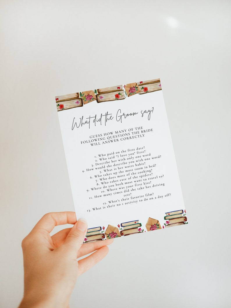 May include: A printable game card with the text "What did the Groom say?" and a list of questions for a bridal shower game. The card is decorated with a watercolor illustration of stacked books and roses.