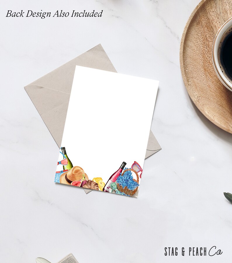 May include: A white card with a watercolor illustration of a picnic basket, wine bottles, fruit, and other picnic items. The text "STAG & PEACH Co." is at the bottom of the card.