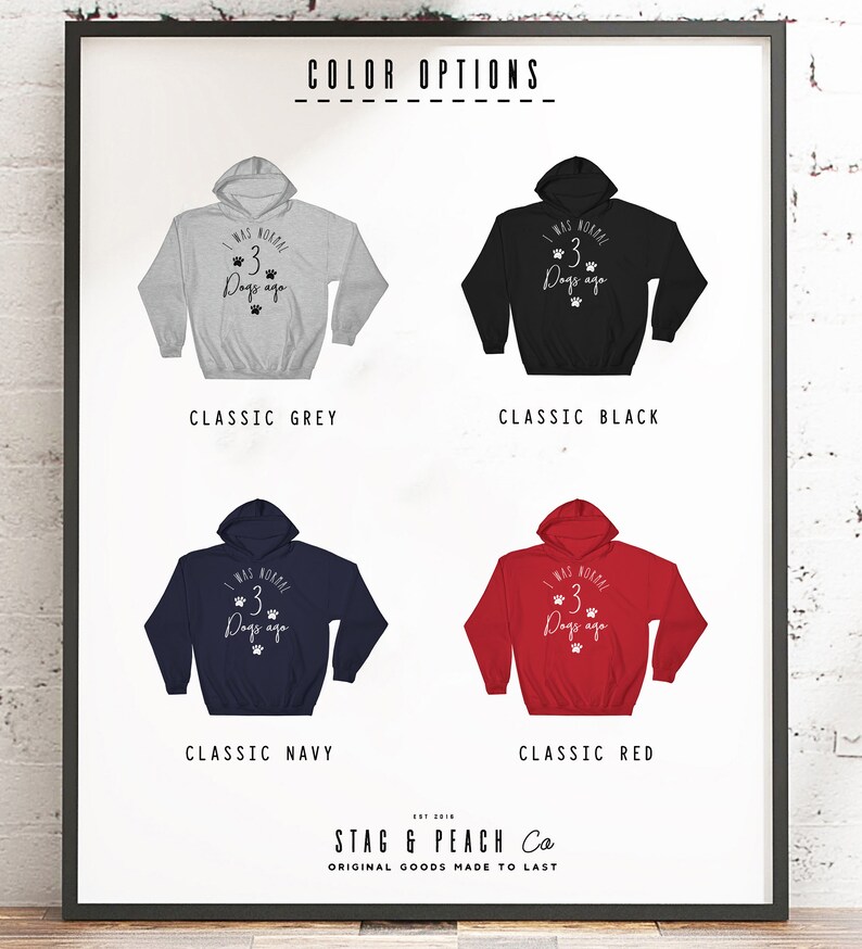 May include: A product mockup showing four different color options for a hooded sweatshirt. The sweatshirt features a graphic print that says "I was normal 3 dogs ago". The colors shown are classic grey, classic black, classic navy, and classic red.