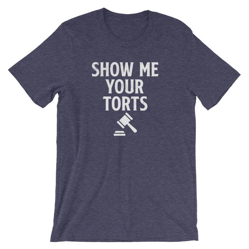 May include: A navy blue t-shirt with the text "Show Me Your Torts" in white lettering. A white gavel icon is below the text.