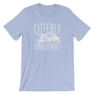 Puede incluir: Camiseta azul claro con un gr&aacute;fico blanco de una nutria y el texto "OTTERLY UNBELIEVABLE CO."