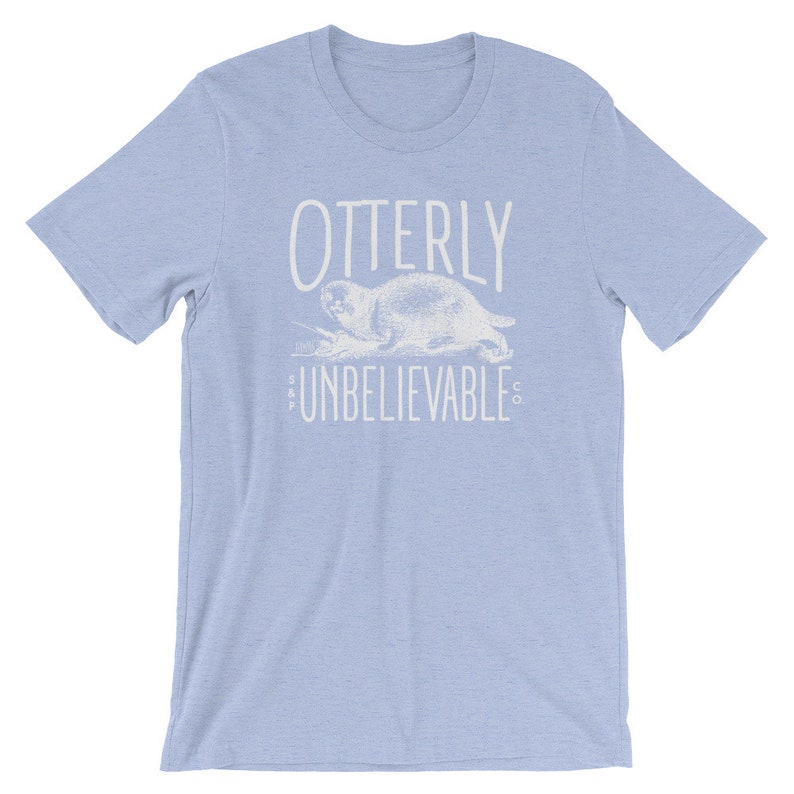 Puede incluir: Camiseta azul claro con un gr&aacute;fico blanco de una nutria y el texto "OTTERLY UNBELIEVABLE CO."