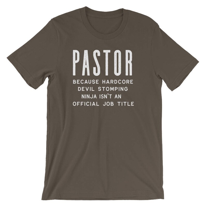 May include: A dark brown t-shirt with the text "PASTOR" in white, followed by the text "Because hardcore devil stomping ninja isn't an official job title".