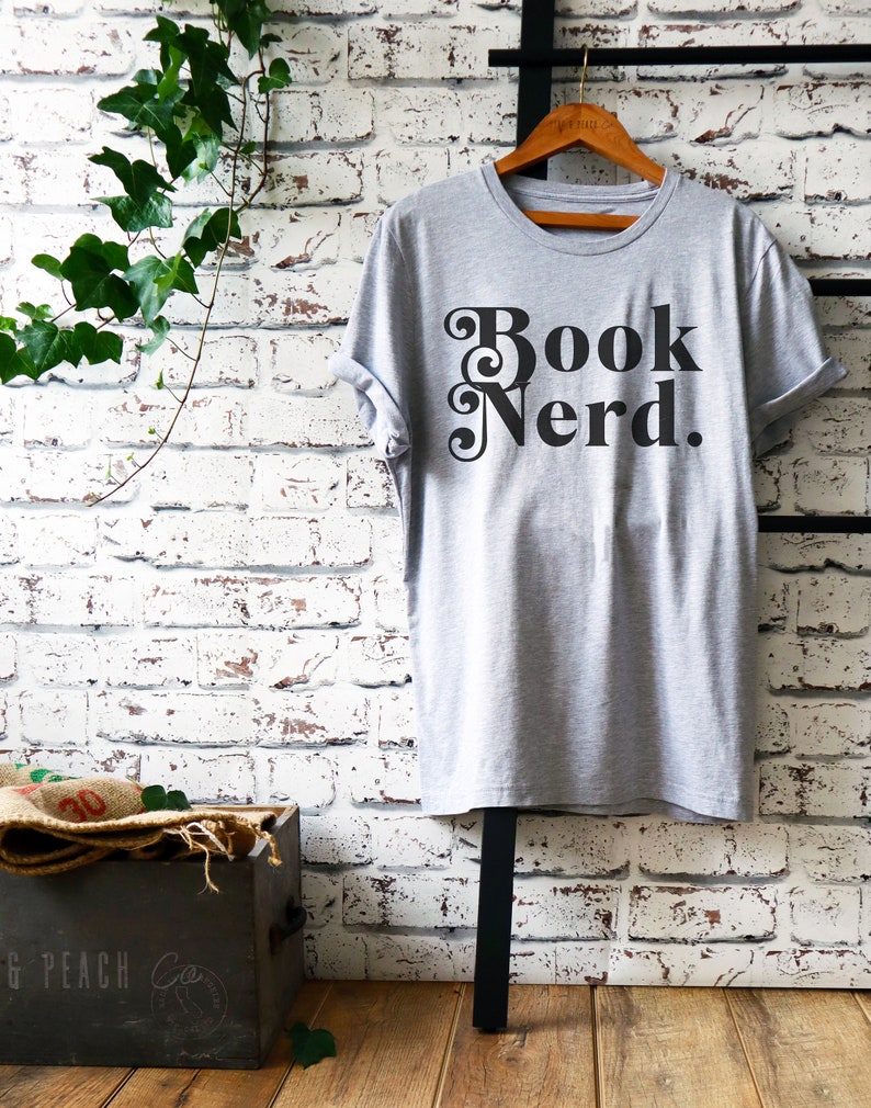 May include: Gray t-shirt with the text "Book Nerd." printed in black with a decorative font.