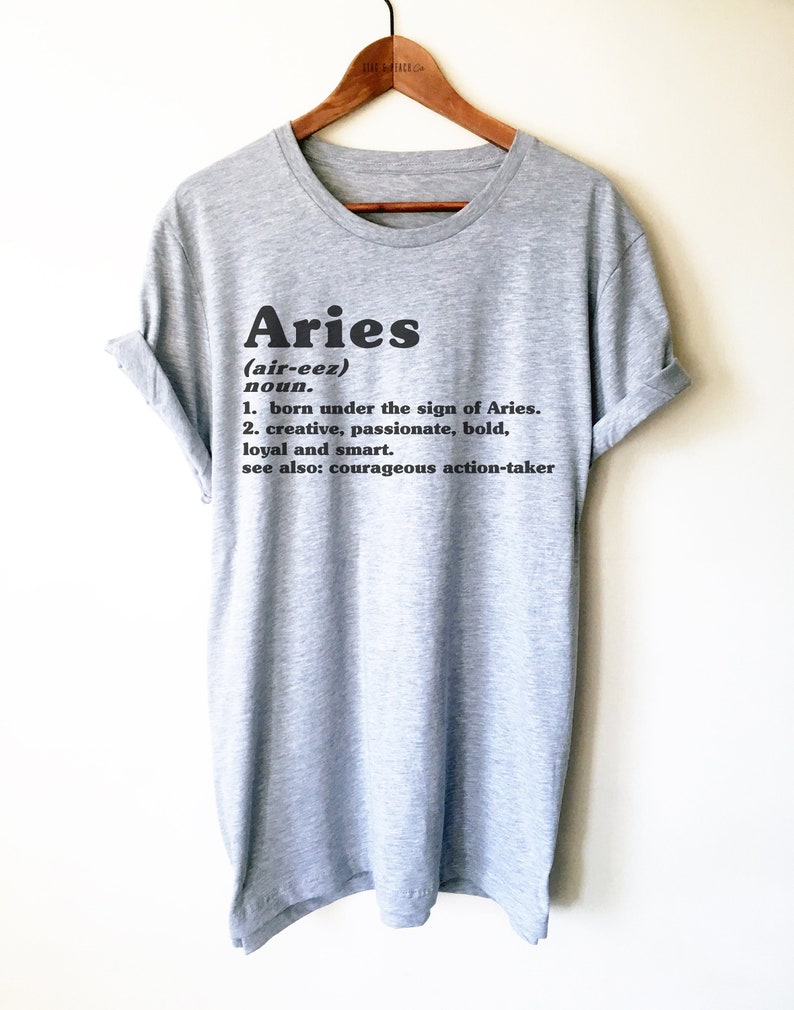 K&ouml;nnte beinhalten: Graues T-Shirt mit einem schwarzen Grafikdesign, das das Wort "Aries" definiert und die Aussprache und Definition des Sternzeichen enth&auml;lt.