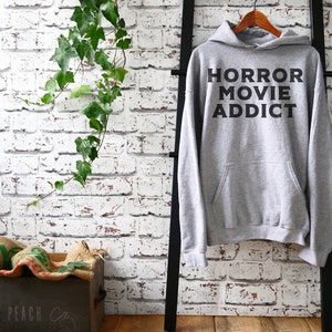 May include: Gray hooded sweatshirt with the text "HORROR MOVIE ADDICT" printed in black.