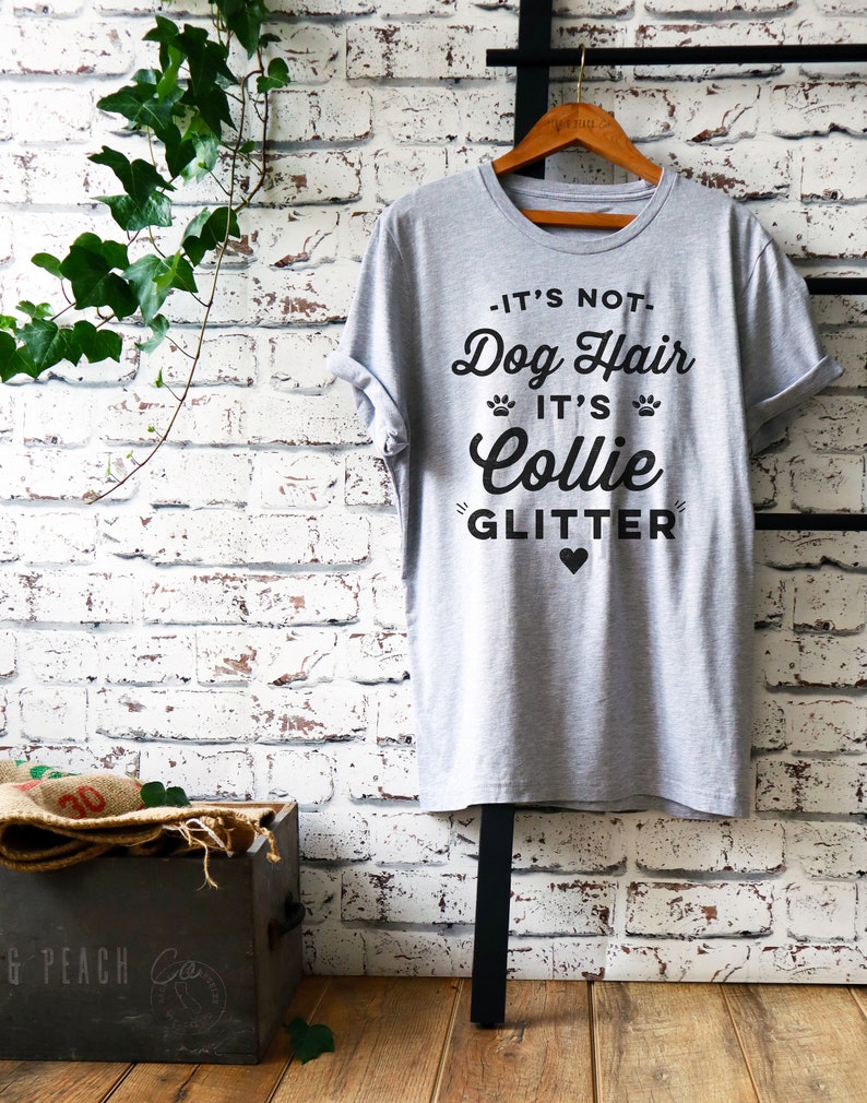 Puede incluir: Camiseta gris con un gr&aacute;fico negro que dice "No es pelo de perro, es brillo de Collie" con un peque&ntilde;o coraz&oacute;n negro.