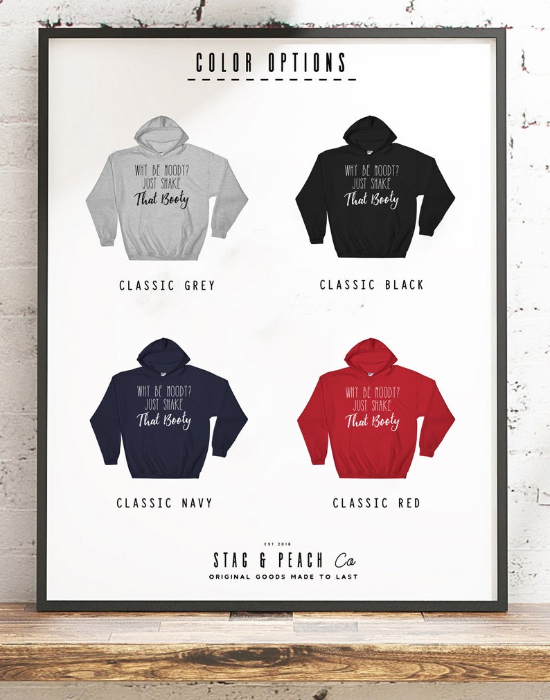May include: Four different color options for a hooded sweatshirt with the text "Why be moody? Just shake that booty" printed on the front. The colors are classic grey, classic black, classic navy, and classic red.