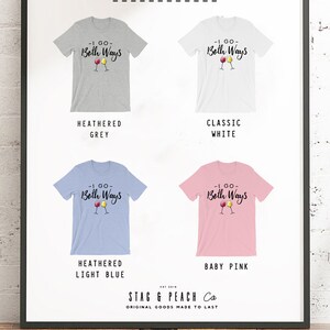 May include: A framed display showcasing four t-shirts in different colors: heathered grey, classic white, heathered light blue, and baby pink. Each shirt features the text "-I GO- Both Ways" with wine glass graphics. The brand name "STAG & PEACH Co" is also visible.