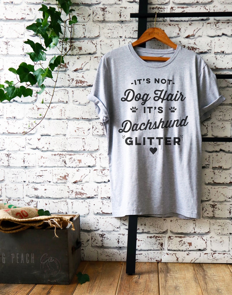 May include: Gray t-shirt with black text that reads "It's not Dog Hair It's Dachshund Glitter" with a small black heart.