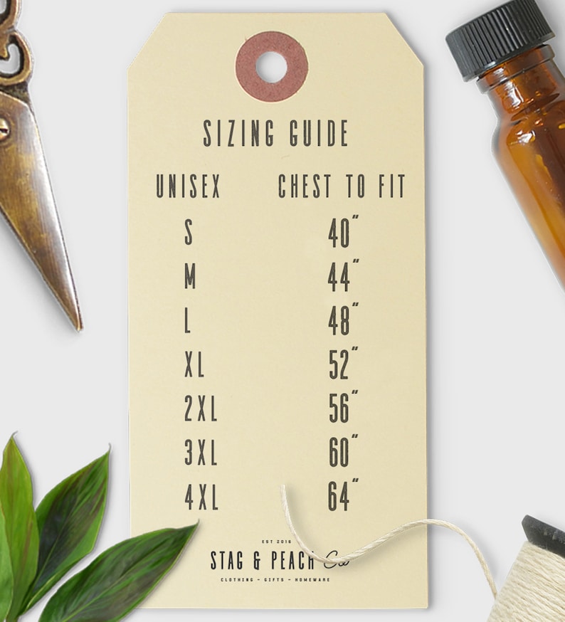 Op de afbeelding: Een beige papieren label met een maattabel voor unisex kleding. Het label geeft maten S tot en met 4XL met de bijbehorende borstmaten in inches. Het label is gemarkeerd met "Stag & Peach Co."