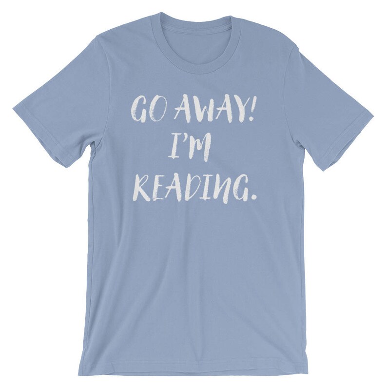 Puede incluir: Una camiseta azul claro con el texto "Go Away! I'm Reading." impreso en blanco.