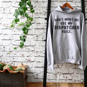 May include: Gray hooded sweatshirt with the text "Don't make me use my dispatcher voice." printed on the front.