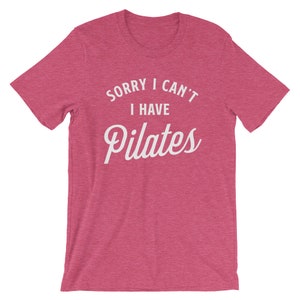 May include: A pink heather t-shirt with the text "Sorry I can't I have Pilates" in white.