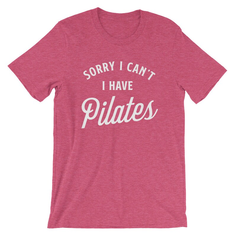 May include: A pink heather t-shirt with the text "Sorry I can't I have Pilates" in white.