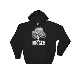 Puede incluir: Sudadera con capucha negra con un gr&aacute;fico de &aacute;rbol blanco y la palabra "HUGGER" impresa debajo del &aacute;rbol.