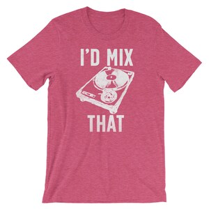 May include: A short-sleeved, pink t-shirt featuring a white graphic of a turntable and the text "I'D MIX THAT". The design is centered on the front of the shirt. The shirt is made of a soft material.