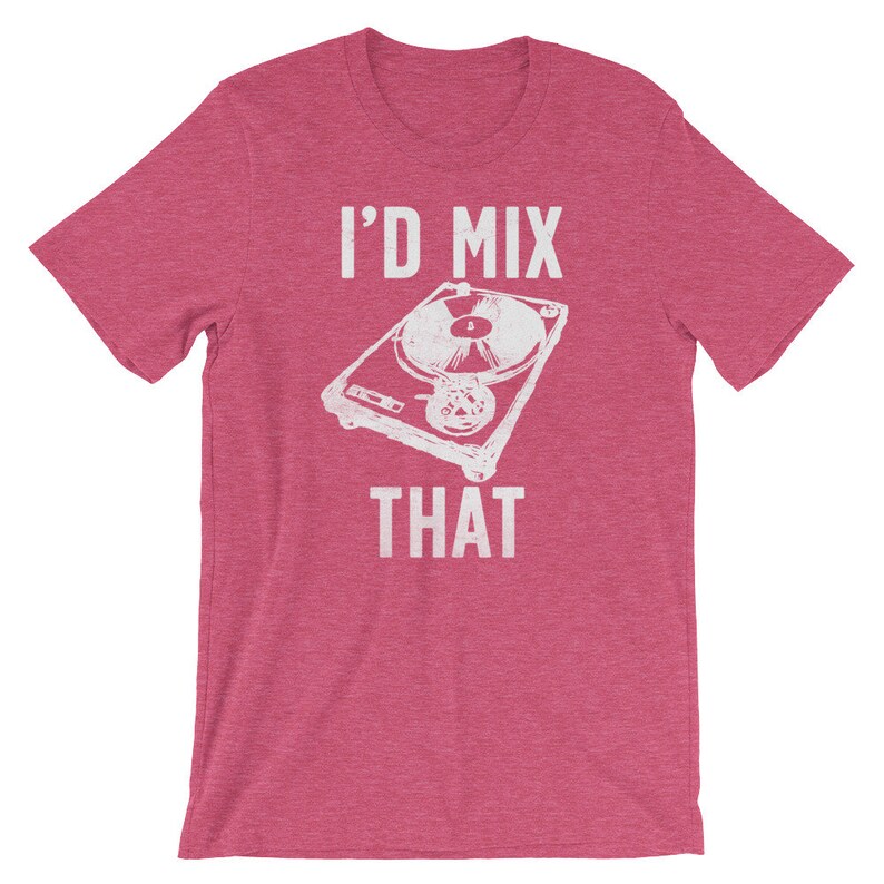 May include: A short-sleeved, pink t-shirt featuring a white graphic of a turntable and the text "I'D MIX THAT". The design is centered on the front of the shirt. The shirt is made of a soft material.