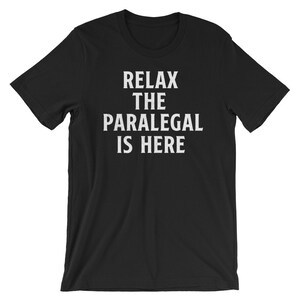 May include: Black t-shirt with white text that reads "Relax the Paralegal is Here."