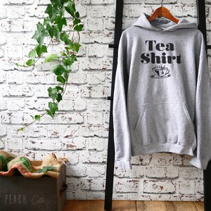 May include: Grey hooded sweatshirt with the text "Tea Shirt" and a black and white illustration of a steaming cup of tea.