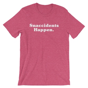 May include: A pink t-shirt with the text "Snaccidents Happen." printed in white.
