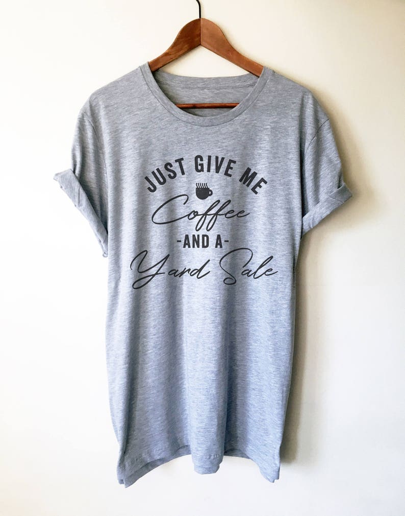 K&ouml;nnte beinhalten: Graues T-Shirt mit dem Text "Just Give Me Coffee -And A- Yard Sale" in schwarzer Schrift. Ein Kaffeetassen-Symbol befindet sich &uuml;ber dem Wort "Coffee".