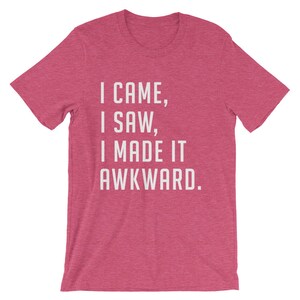 Puede incluir: Camiseta rosa con la frase blanca: "I CAME, I SAW, I MADE IT AWKWARD". La camiseta tiene mangas cortas y cuello redondo, ideal para un look casual.