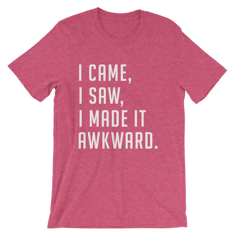 Puede incluir: Camiseta rosa con la frase blanca: "I CAME, I SAW, I MADE IT AWKWARD". La camiseta tiene mangas cortas y cuello redondo, ideal para un look casual.