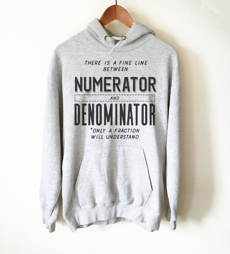 Puede incluir: Una sudadera con capucha gris con el texto "THERE IS A FINE LINE BETWEEN NUMERATOR AND DENOMINATOR *ONLY A FRACTION WILL UNDERSTAND" impreso en la parte delantera.