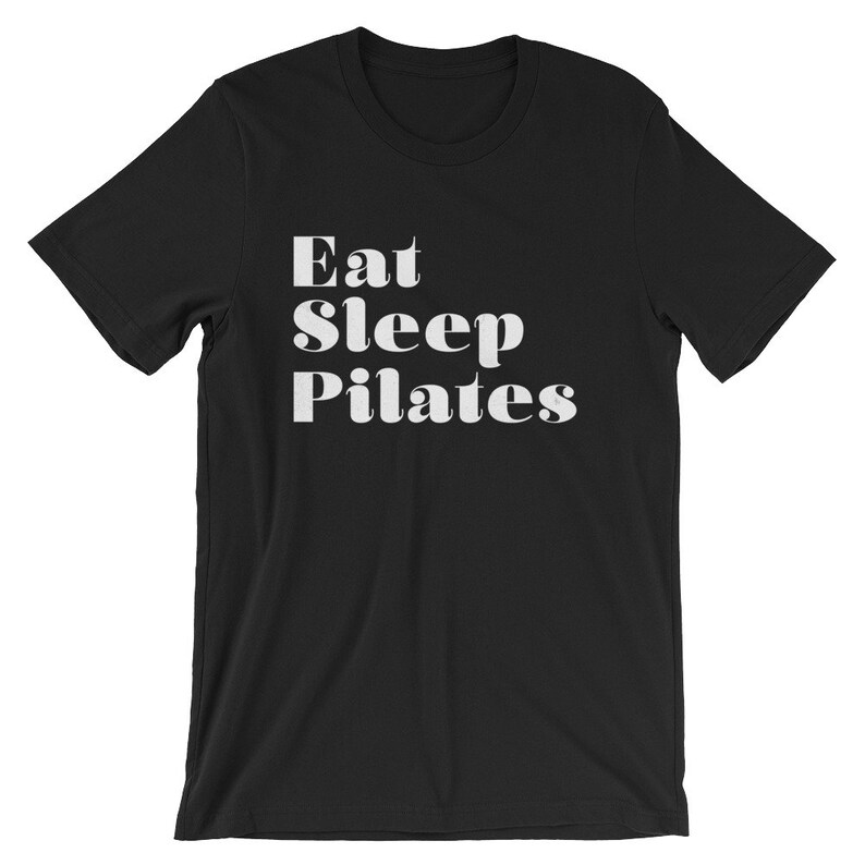 Pode incluir: Camiseta preta com texto branco que diz "Eat Sleep Pilates".