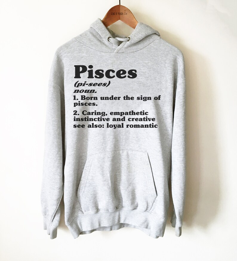 May include: Gray hooded sweatshirt with the word "Pisces" in black bold letters and a definition of the word. The definition includes the phrase "Born under the sign of pisces." and "Caring, empathetic instinctive and creative."