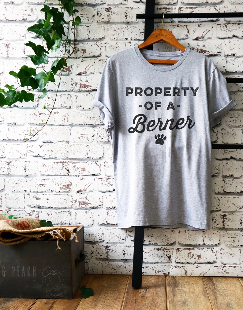 May include: Gray t-shirt with the text "PROPERTY -OF A- Berner" and a paw print.