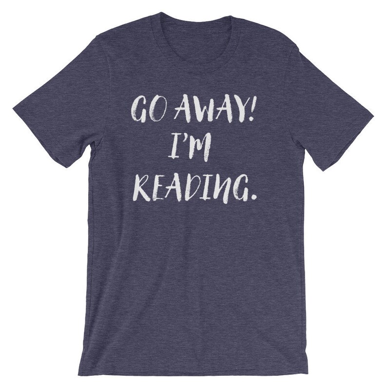 Puede incluir: Una camiseta azul marino con el texto "GO AWAY! I'M READING." en blanco.