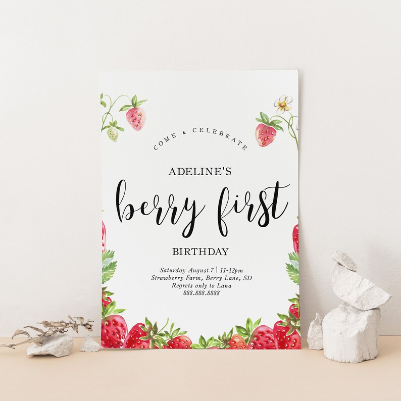 May include: A white card with a strawberry border and the text "COME & CELEBRATE ADELINE'S berry first BIRTHDAY Saturday August 7 11-12pm Strawberry Farm, Berry Lane, SD Regrets only to Lana 888.888.8888"
