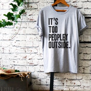 Puede incluir: Camiseta gris con texto negro que dice "It's Too Peopley Outside."