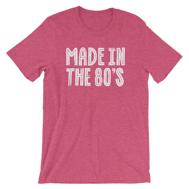 May include: A pink heather t-shirt with the text "MADE IN THE 80'S" in white.