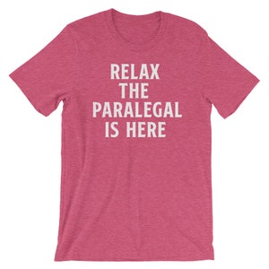 May include: A pink heather t-shirt with the text "Relax the Paralegal is Here" in white.