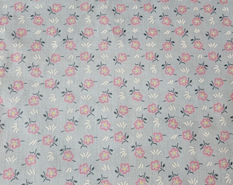 May include: A light blue fabric with a repeating pattern of small pink flowers with yellow centers and black stems. The flowers are arranged in a staggered pattern.
