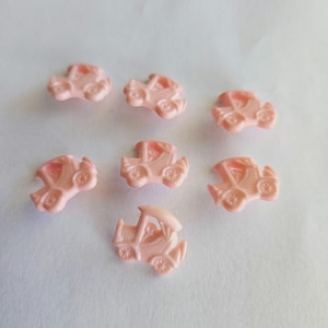 Puede incluir: Siete botones de plástico rosa con forma de coche. Los botones tienen un diseño en relieve y miden aproximadamente 2,5 cm de diámetro.