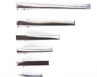 May include: Set of six silver metal hair clips in various sizes. The clips are arranged in a staggered pattern, with the largest clip at the top and the smallest clip at the bottom.