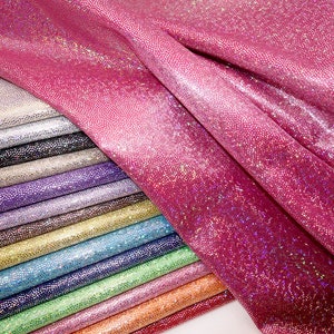 May include: A stack of iridescent fabric in various colours, including pink, purple, blue, green, and orange. The fabric has a subtle sparkle and a textured surface.